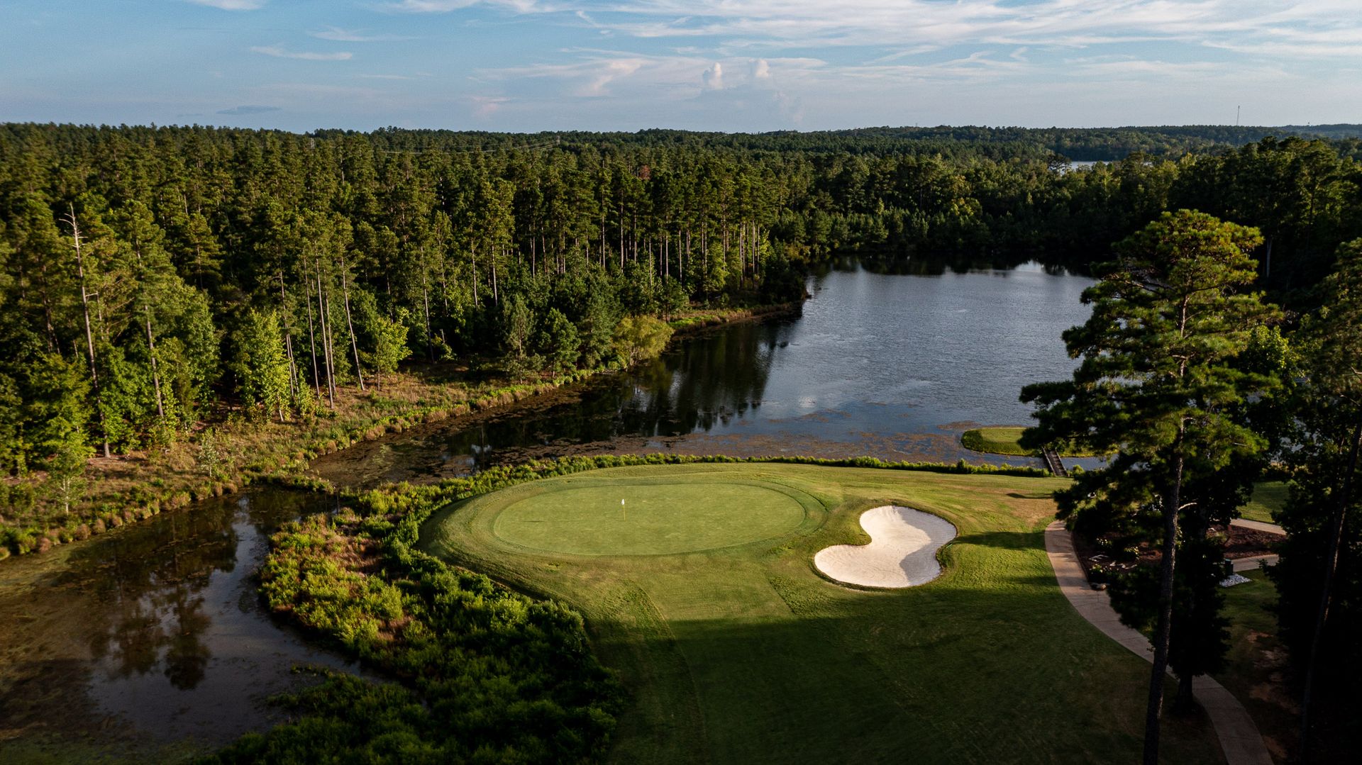 Aerial view of Edgewater Golf Club hole 3 with pristine green, sand bunker, and lake backdrop