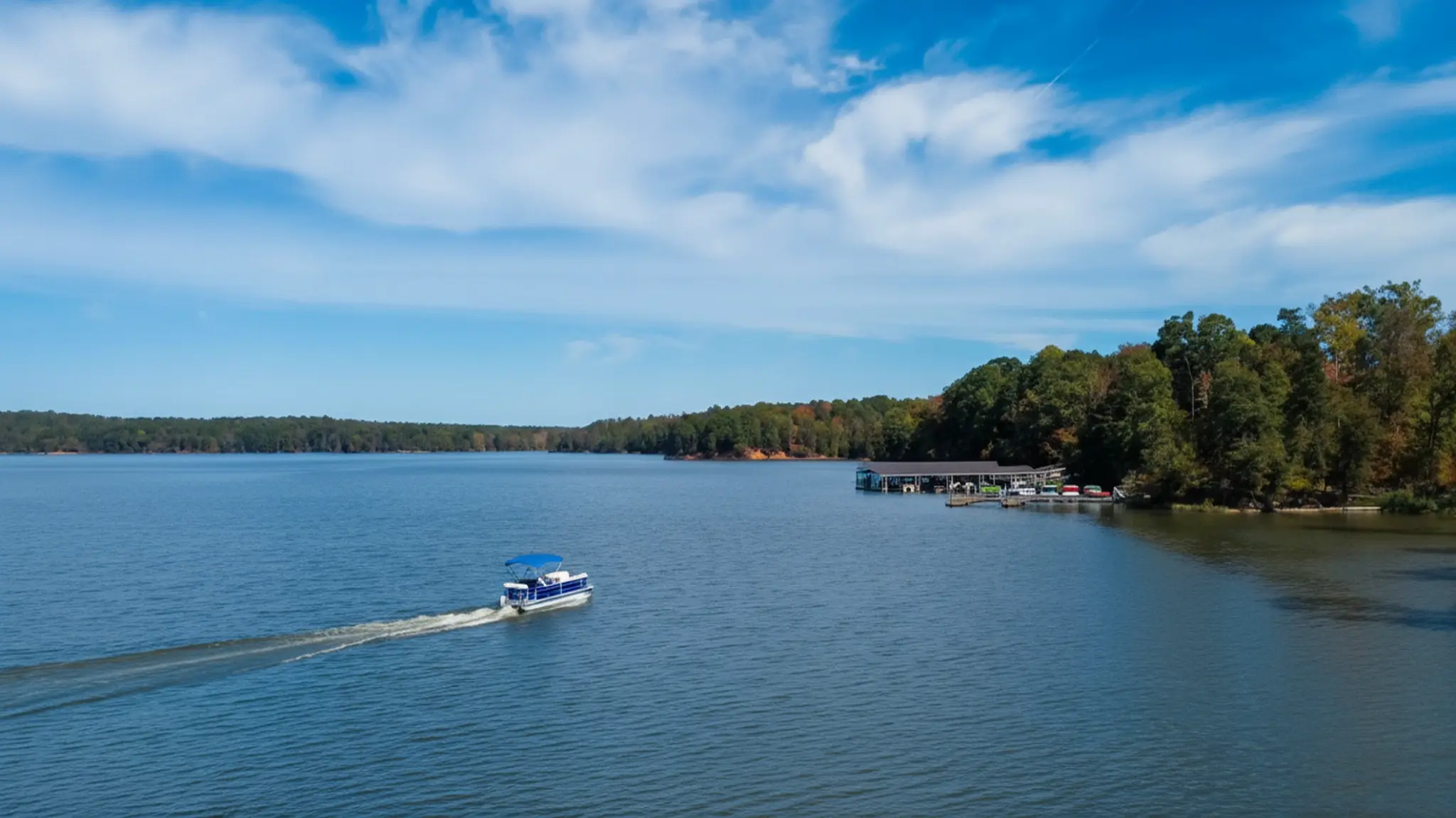 Beautiful view of Fishing Creek Lake with boat on water, marina, and tree-lined shores